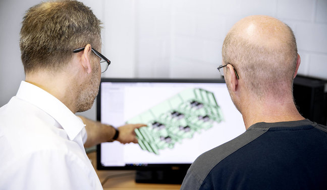 Person A zeigt Person B die CAD-Visualisierung eines Produktmodells auf einem Bildschirm